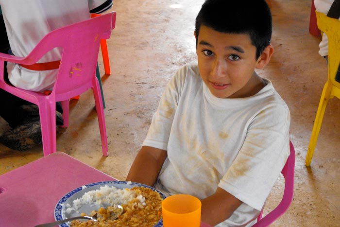 A happy young boy enjoying a nutritious meal made from Breedlove food.